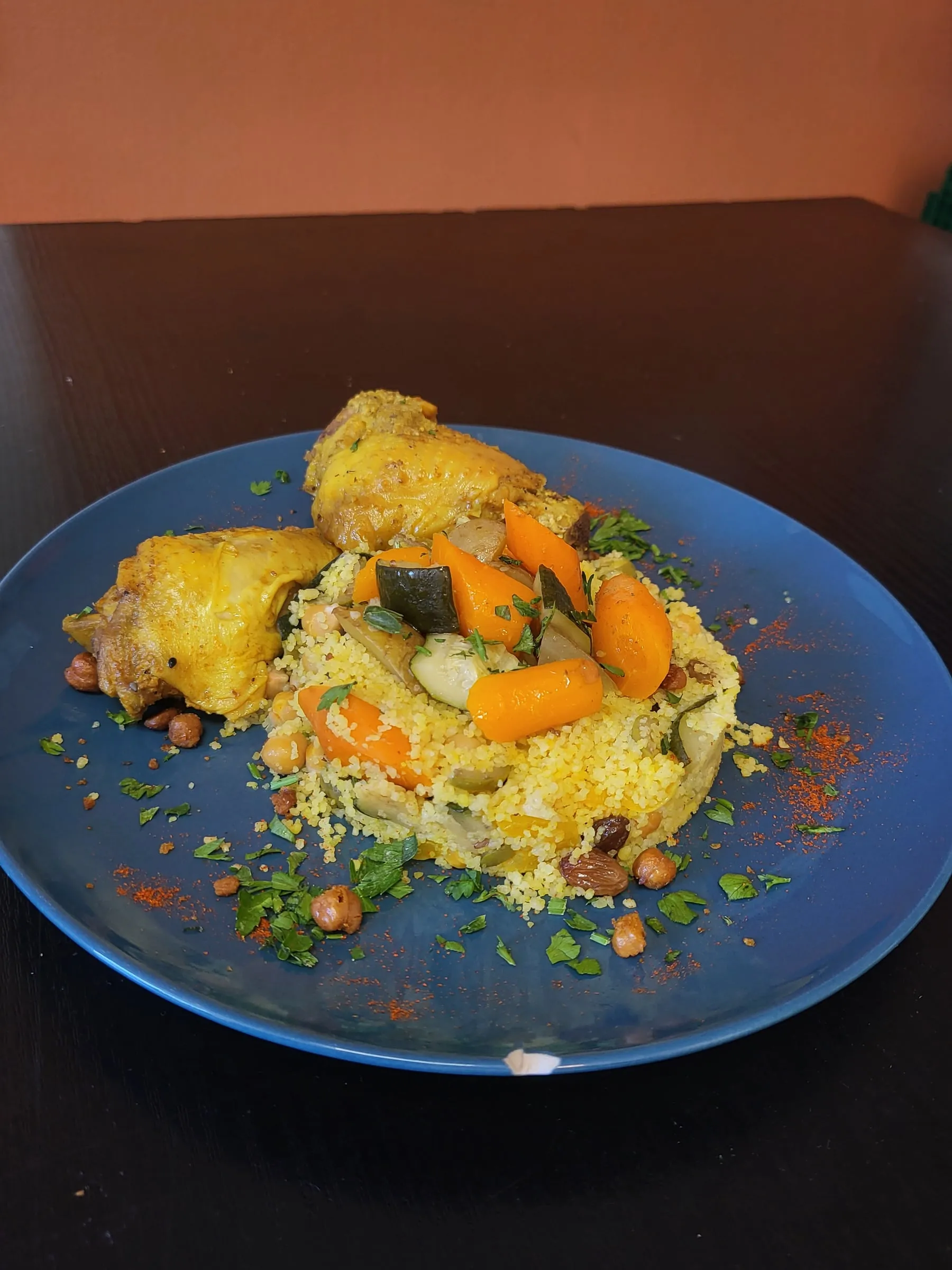 Couscous de légumes et poulet dressé dans une assiette bleue
