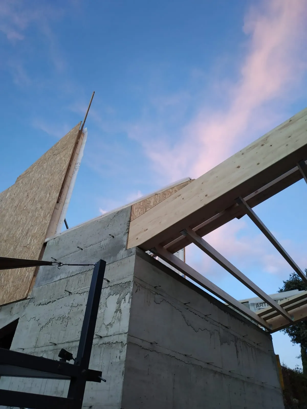 Charpente bois vue en contre-plongée sur un ciel de fin de journée