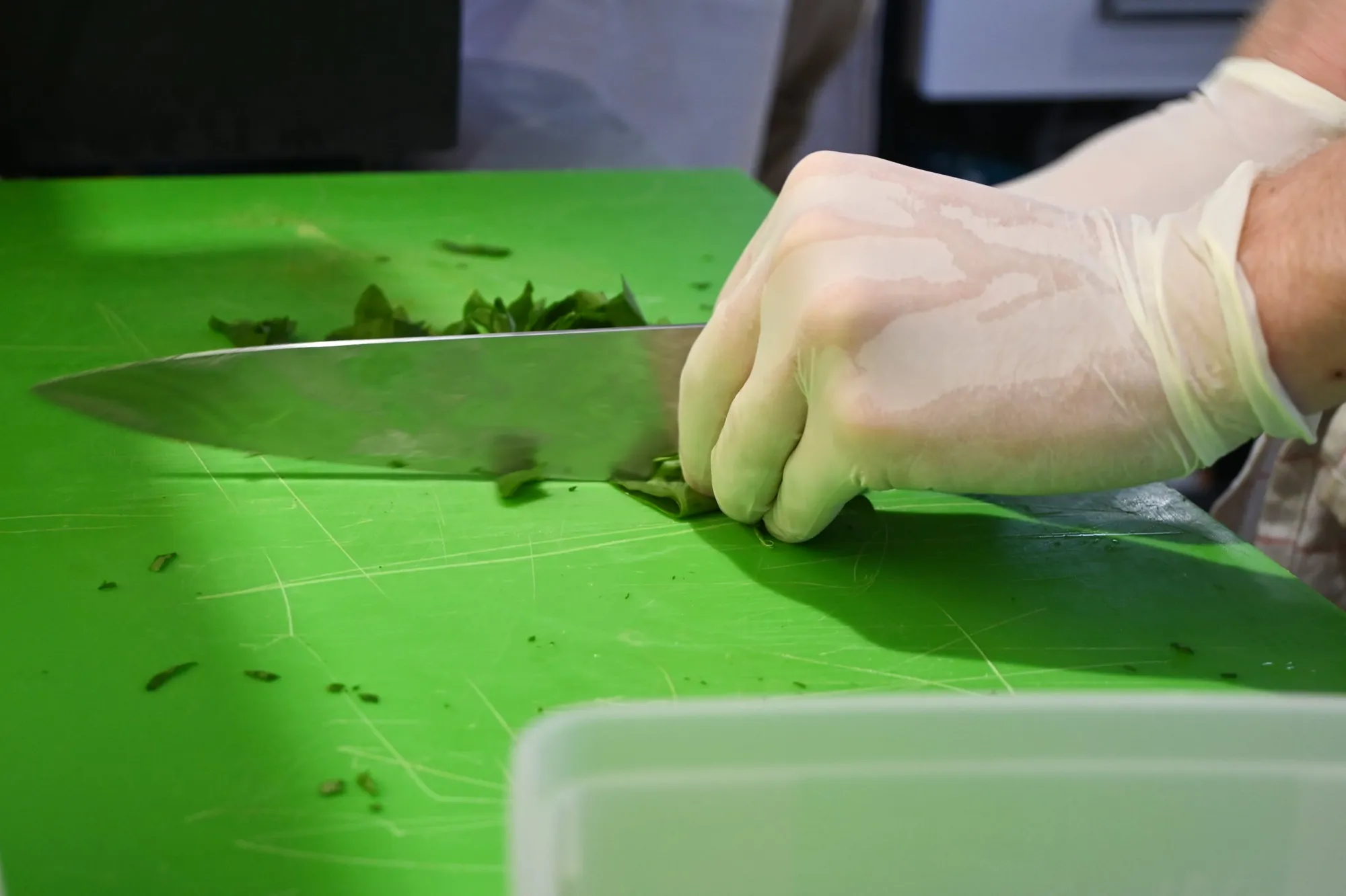 Mains gantées ciselant des herbes fraîches sur une planche à découper